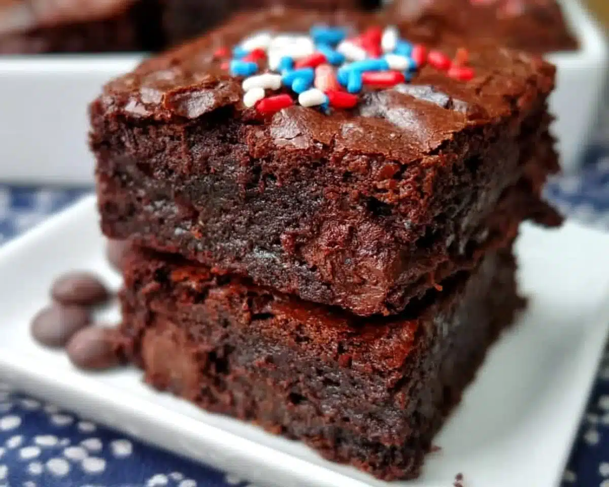 Ultimate easy brownies topped with chocolate icing on a plate.
